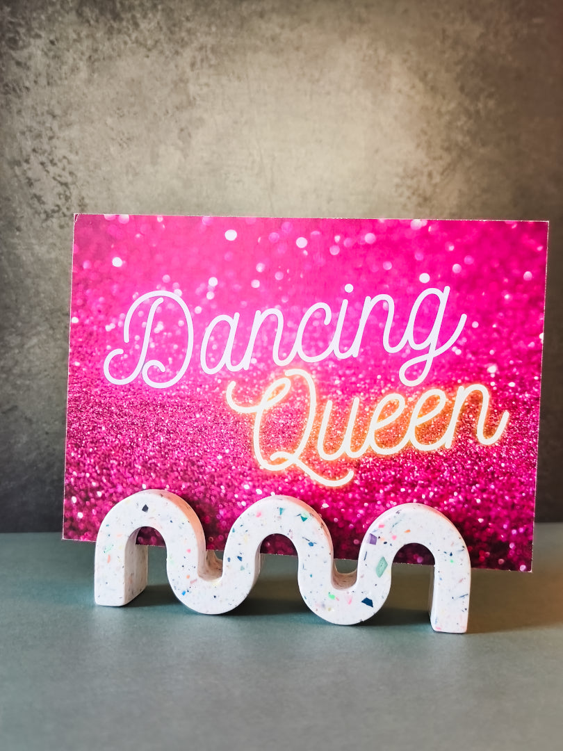 support photo wavy en jesmonite, en forme de vague, blanc terrazzo multicolore, présenté avec une carte postale dancing queen de la cigalélée