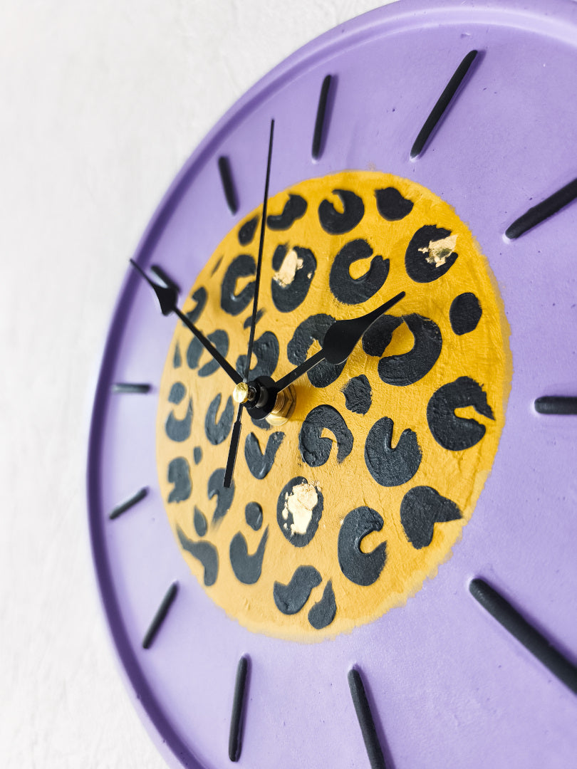 vue rapprochée d'une horloge Odette customisée par Koa Artwork cadran violet motifs léopard aiguilles noires