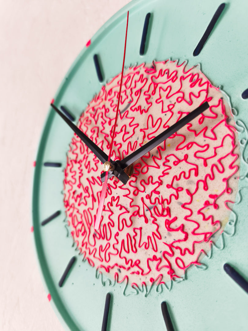 vue rapprochée d'une horloge Odette customisée par Koa Artwork cadran couleur menthe motifs fuchsia aiguilles noires