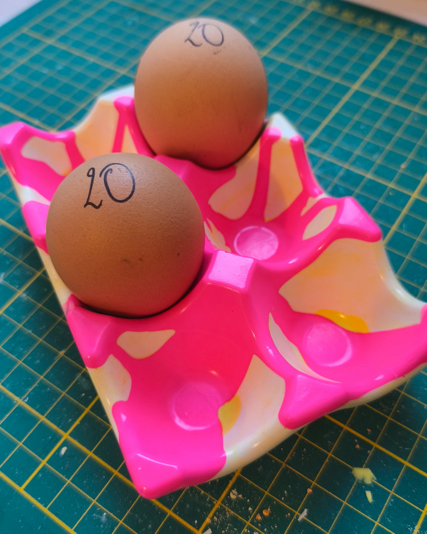 support à oeufs rose fluo marbré blanc et jaune, présenté avec deux vrais oeufs, jesmonite, hey denise