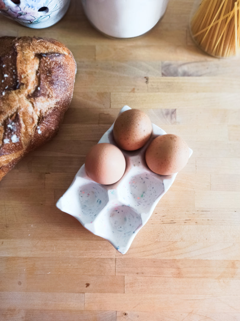 support à oeufs en jesmonite, blanc terrazzo multicolore, présenté avec trois vrais oeufs, prise de vue du dessus