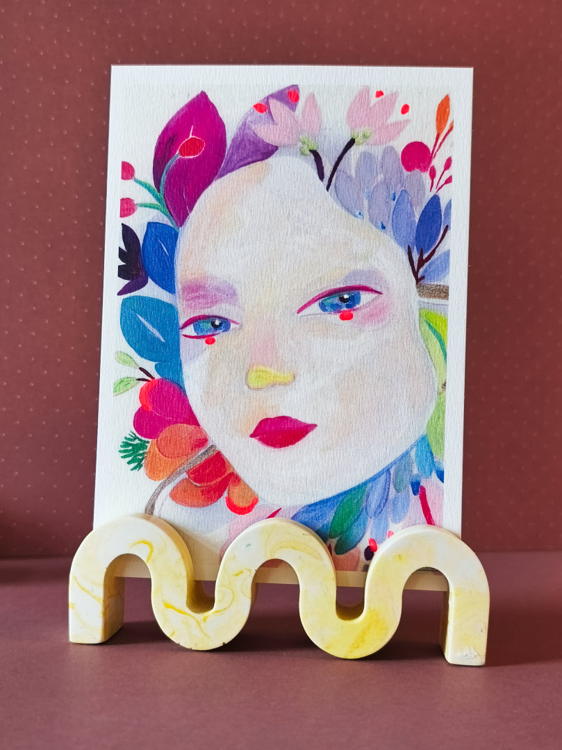 support photo wavy en jesmonite, en forme de vague, couleur jaune marbré, présenté avec une carte postale d'izumi idoia
