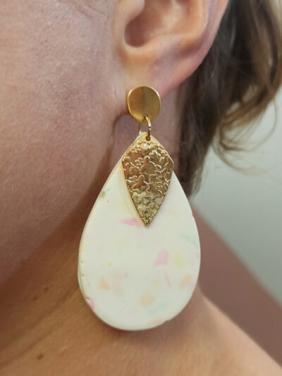 mise en situation portées de boucles d'oreilles pendantes longues en forme de grandes gouttes en Jesmonite de couleur blanc terrazzo multicolore avec un pendentif en forme de losange texturé doré anguleux attaches puces rondes lisses acier inoxydable doré